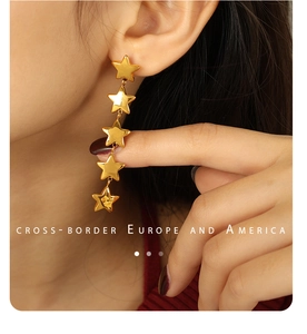 Gros plan de boucles d'oreilles pendantes en or 18 carats avec cinq étoiles polies