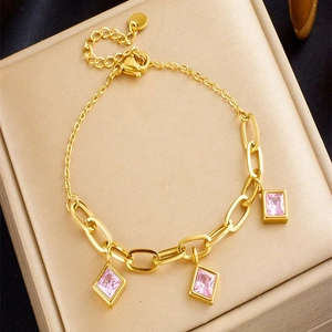 Detail of gold-plated paperclip bracelet featuring pink cubic zirconia square charms