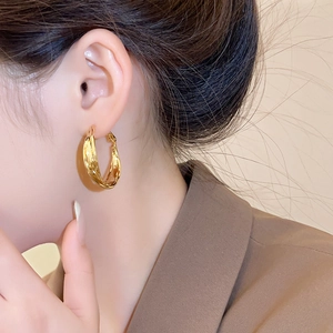 Detailed view of layered gold hoop earrings on a model wearing a brown blazer
