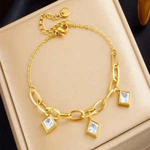 Detail of gold paperclip chain bracelet featuring three square zircon stone charms