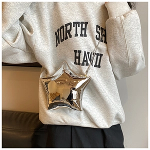 Star-shaped silver acrylic mini box bag with metal chain strap worn by a model