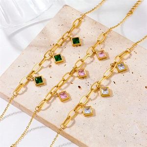 Gold chain necklaces with emerald, pink, and white square zircon pendants on stone