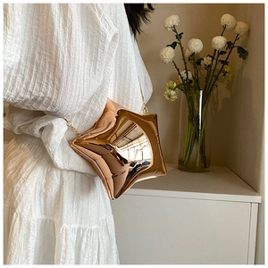 Detail of a shiny star-shaped acrylic mini bag with mirror finish and gold chain strap