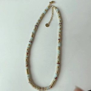Détail du collier de perles artisanal avec pierres bleu clair et perles d'espacement dorées