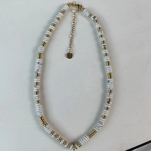 Détail macro de perles de marbre blanc et d'entretoises dorées sur un collier perlé