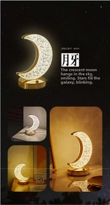 Detail of crescent moon lamp with crystal texture shade on golden metal base
