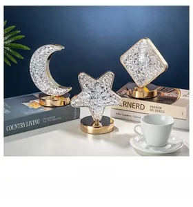 Three crystal star and moon night lights with gold metal bases on decorative books
