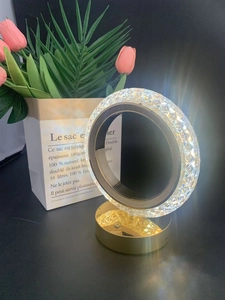 Detail of crystal ring lamp with gold metal base and diamond-cut textured light reflection