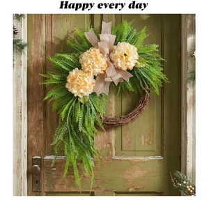 Detail of faux yellow hydrangea wreath with burlap bow on rustic green wooden door