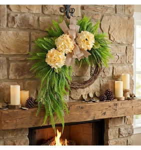 Close-up of artificial hydrangea wreath with burlap bow on a rustic stone fireplace