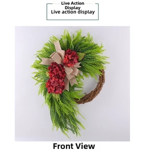 Detail of red hydrangea wreath with green leaves and burlap bow on grapevine base