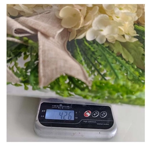 Macro view of artificial cream hydrangea wreath showing 426g weight on a digital scale