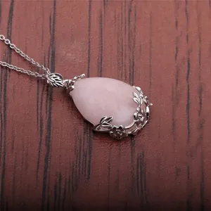 Macro view of teardrop rose quartz pendant with intricate silver floral metalwork detail
