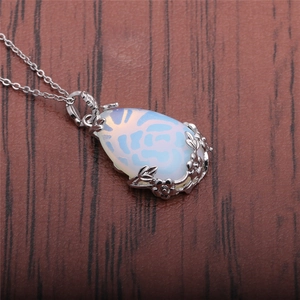 Water drop moonstone necklace with silver floral filigree detail on wooden background