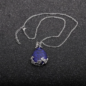 Close-up of teardrop blue stone pendant with silver floral and vine metalwork detail