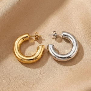 Polished thick C-shaped hoop earrings in gold and silver finish on champagne silk fabric