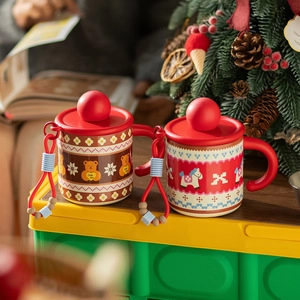 Close-up of Christmas ceramic mugs with festive bear prints and red spherical handles
