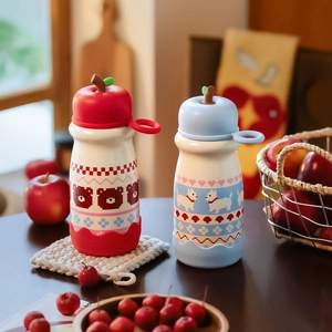 Detail of cartoon thermal cups with apple-shaped lids and non-slip silicone bases