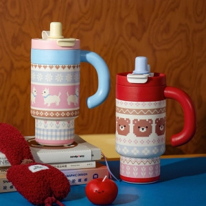 Detail of insulated tumblers with knit patterns and oversized handles on a wooden table