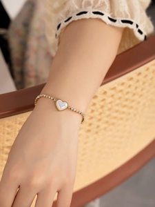 Détail d'un bracelet doré avec pendentif cœur et cristaux brillants sur le poignet
