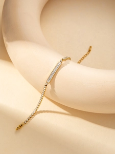 Vue détaillée du bracelet doré ajustable serti de cristaux sur un support beige