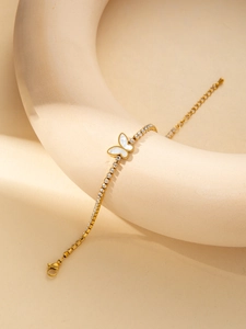 Détail du bracelet noeud doré avec nacre blanche et chaîne de tennis en cristaux brillants