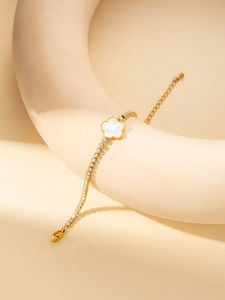Détail du bracelet en titane doré avec trèfle en nacre et zircons brillants