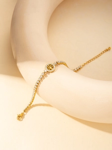 Détail d'un bracelet arbre de vie doré avec zircons blancs et chaîne ajustable sur un support