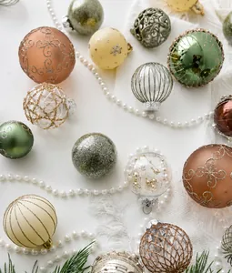 Detailed view of assorted champagne and green Christmas ornaments on white fabric