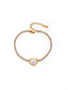 Détail d'un bracelet tennis doré avec breloque cœur en nacre et pierres de zircon