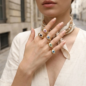 Detailed view of colorful evil eye resin rings with gold plating on model's fingers