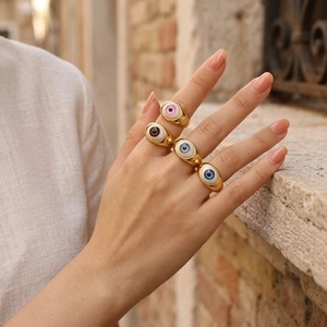 Set of four gold evil eye resin rings in various colors worn by a model in retro style