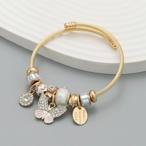 Macro detail of gold-plated bangle featuring a sparkling butterfly charm and crystals