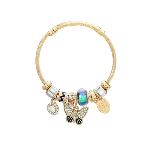 Macro detail of golden spiral bracelet with rhinestone butterfly and glass bead charms