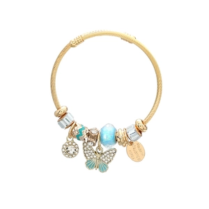 Detailed macro view of butterfly charm and blue glass bead on golden cable bracelet