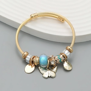 Detail of gold beaded bangle featuring a blue shimmer bead and butterfly charm pendant