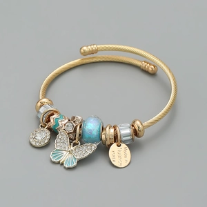 Detail of gold twisted bangle with butterfly pendant and blue crystal glass beads