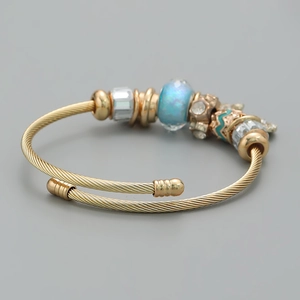 Macro detail of gold wire bracelet with blue opal bead and sparkling crystal spacers