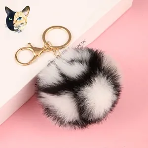 Macro detail of a 8cm black and white spotted faux rabbit fur ball with gold keychain