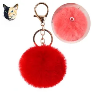 Dettaglio di un pompon rosso in finta pelliccia di coniglio con chiusura dorata