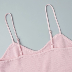 Close-up of pink knitted dress with adjustable straps and fine ribbed texture