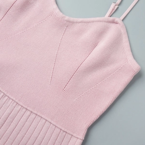 Detail of pink knitted dress featuring V-shaped pattern and ribbed texture with thin straps
