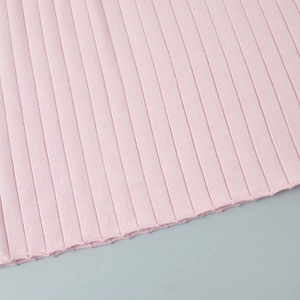 Close-up of pink knitted ribbed fabric texture showing the vertical stripe detail of the dress