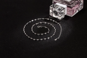 Close-up of S925 sterling silver water wave chain with lobster clasp on black texture