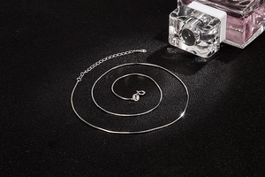 Detailed view of silver S925 snake chain with lobster clasp on a textured dark background