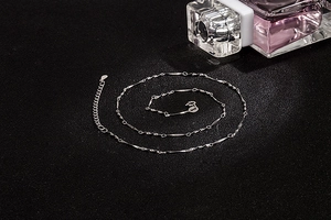Macro shot of S925 sterling silver twist link chain necklace on textured black surface