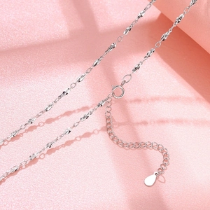 Macro detail of S925 sterling silver twisted leaf chain with lobster clasp and drop charm