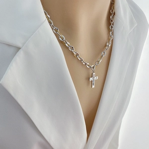 Two-tone cross pendant necklace with baguette zircon stones on mannequin display