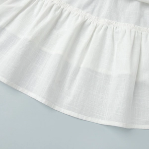 Detail of white cotton fabric hem featuring fine pleats and neat stitching quality