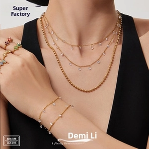 Macro detail of gold layering necklace and bracelet set with teardrop charms